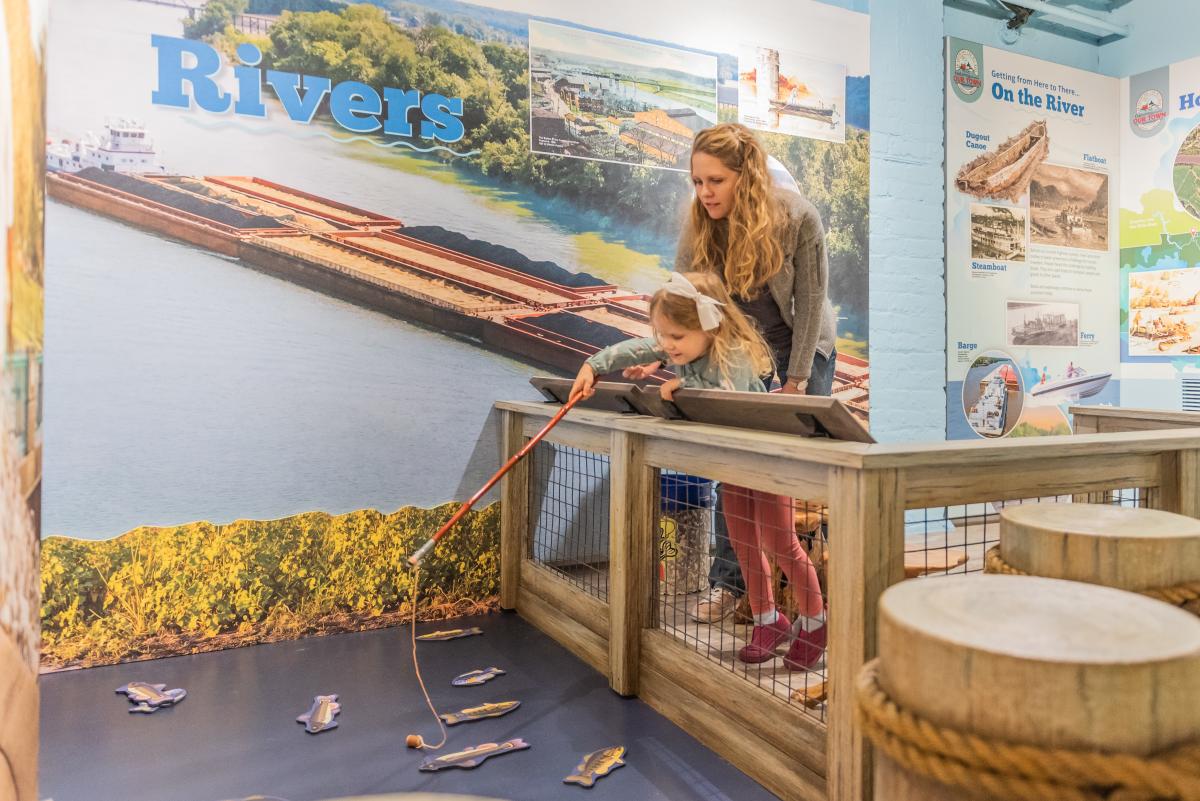 mom and daughter "fishing" in a museum exhibit