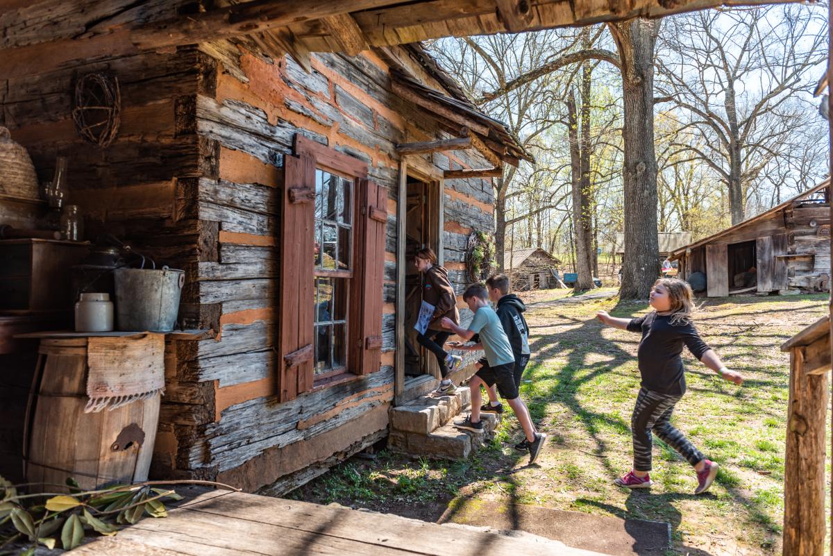 children enter log cabin at Historic Collinsville