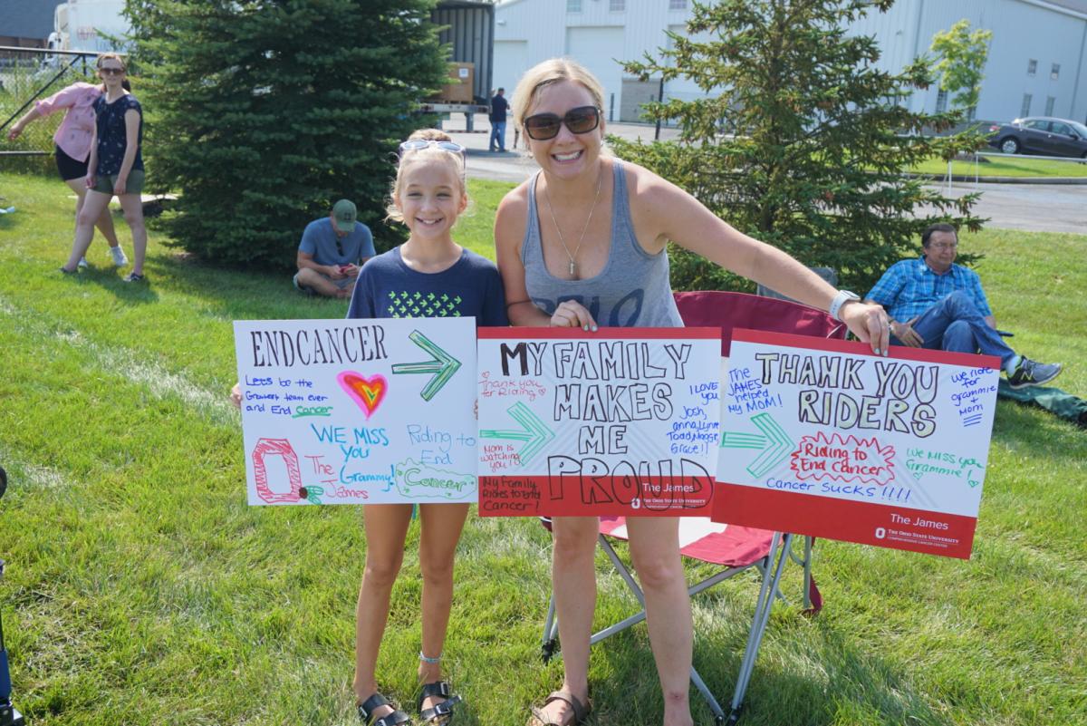 Mom and daughter hold signs for Pelotonia riders