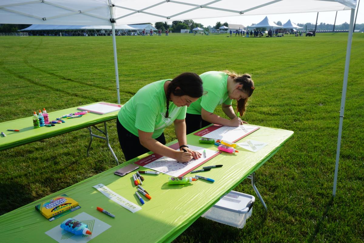 Two girls make signs for Pelotonia