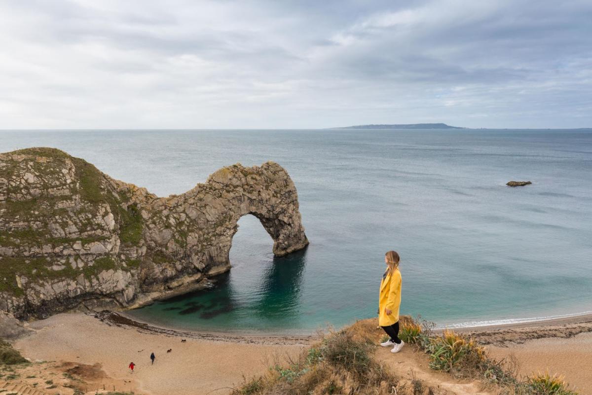 Woman standing on cliffs overlooking Durdle Door in Dorset