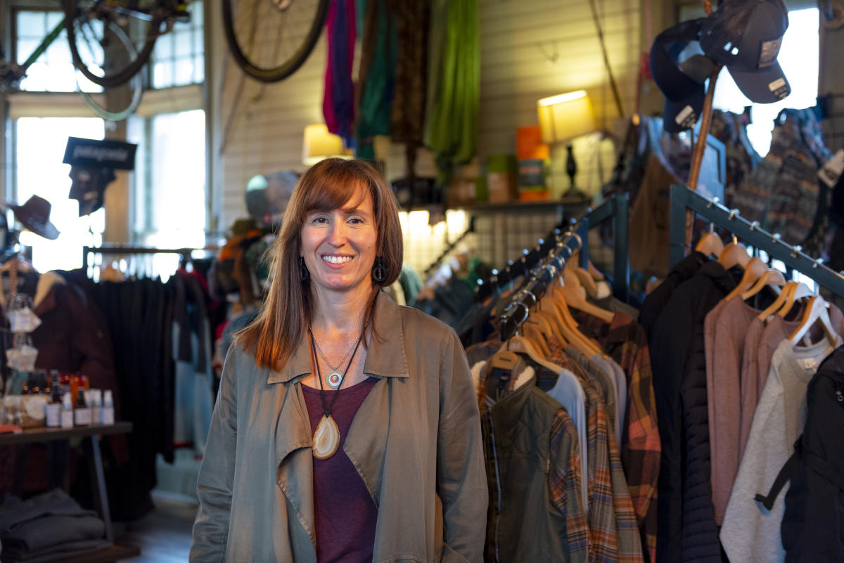 Cara Hall of Fort Wayne Outfitters in Fort Wayne, Indiana standing in her shop with outdoor recreation apparel and gear in the background.