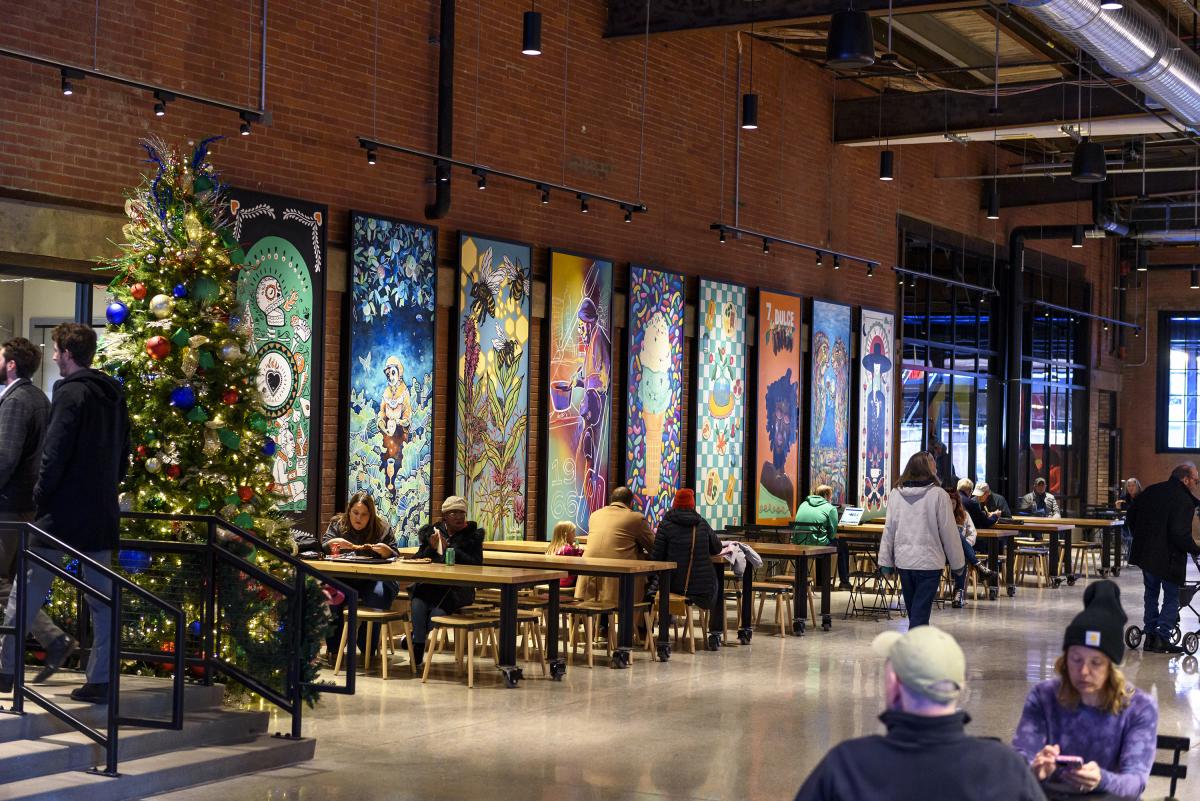 people eating at tables next to murals at union street market
