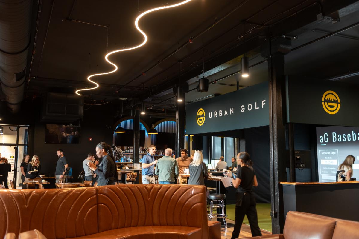Lively atmosphere at Urban Golf showing people dining and using the golf simulators in Fort Wayne, Indiana