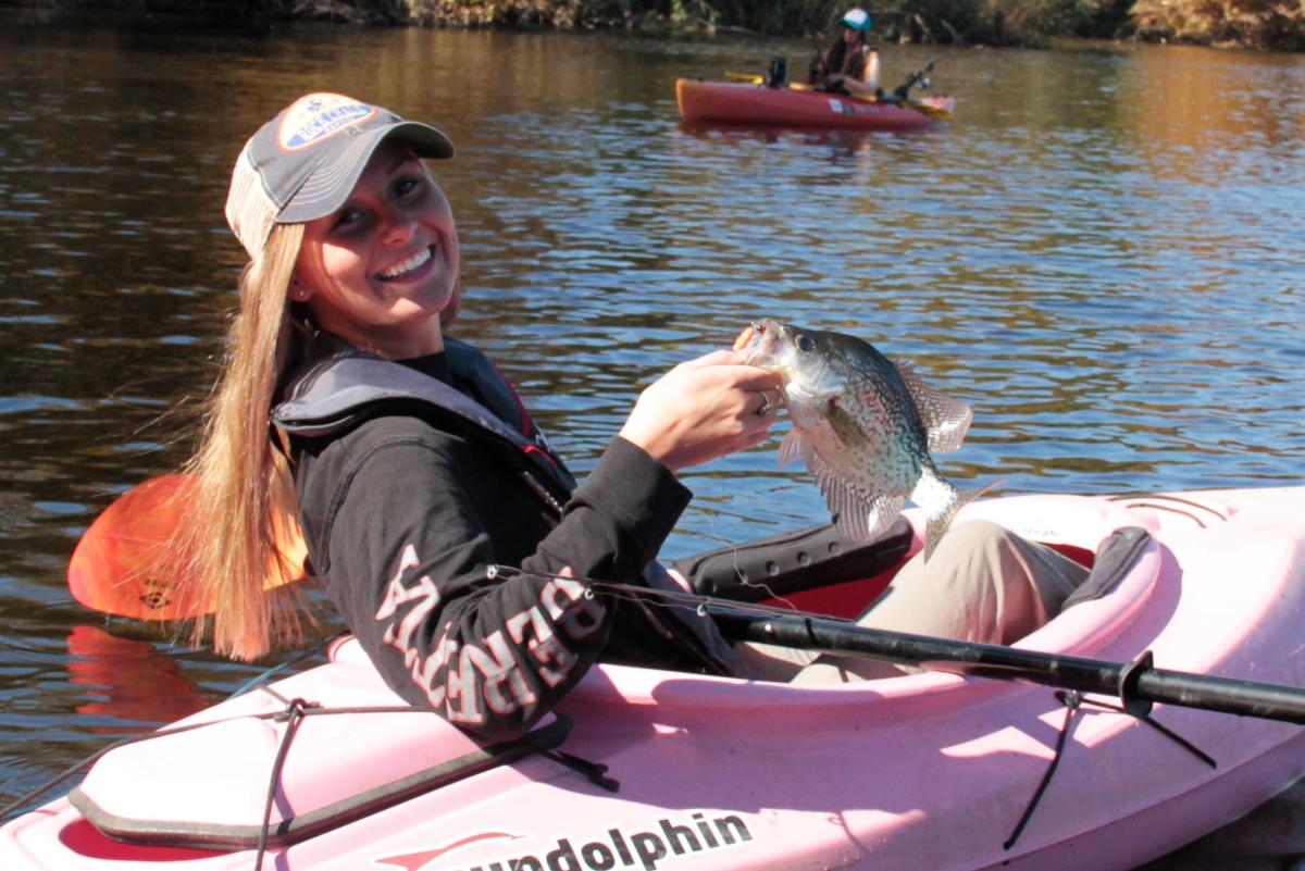 girl in kayak holding a fish
