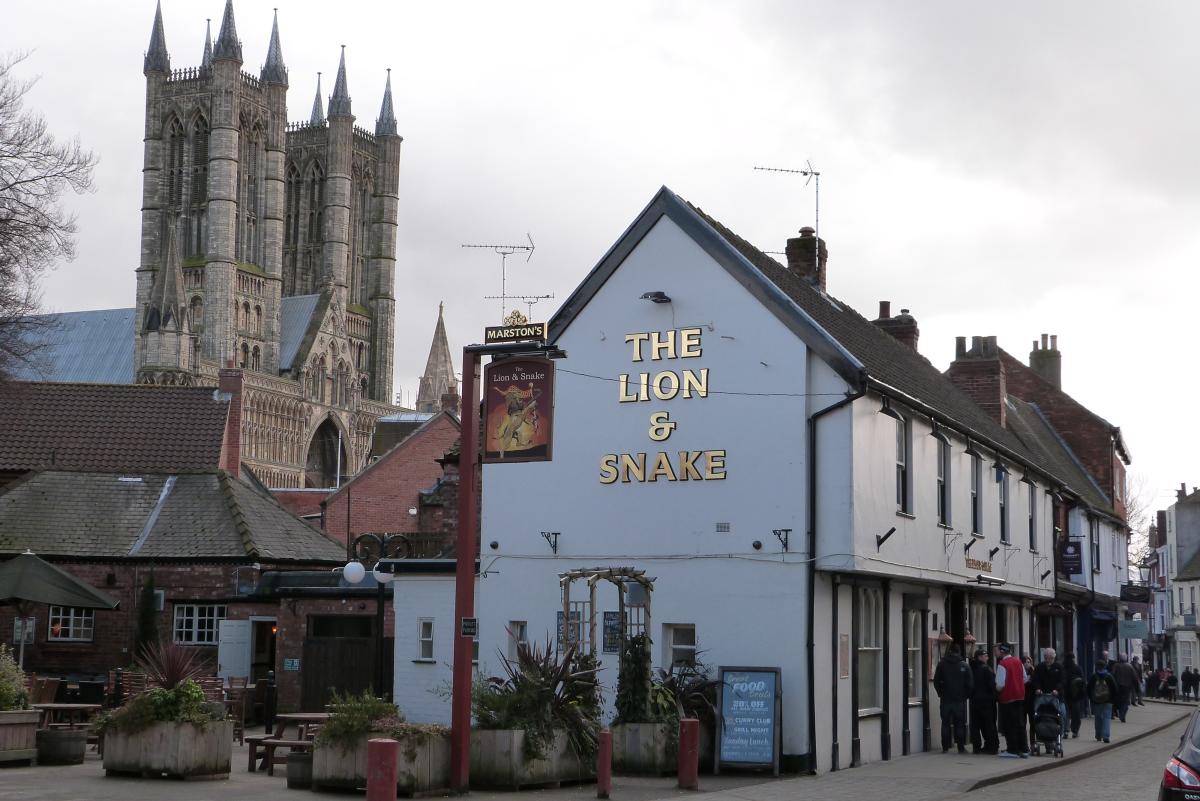 a group of people gathered outside the entrance of The Lion & Snake pub