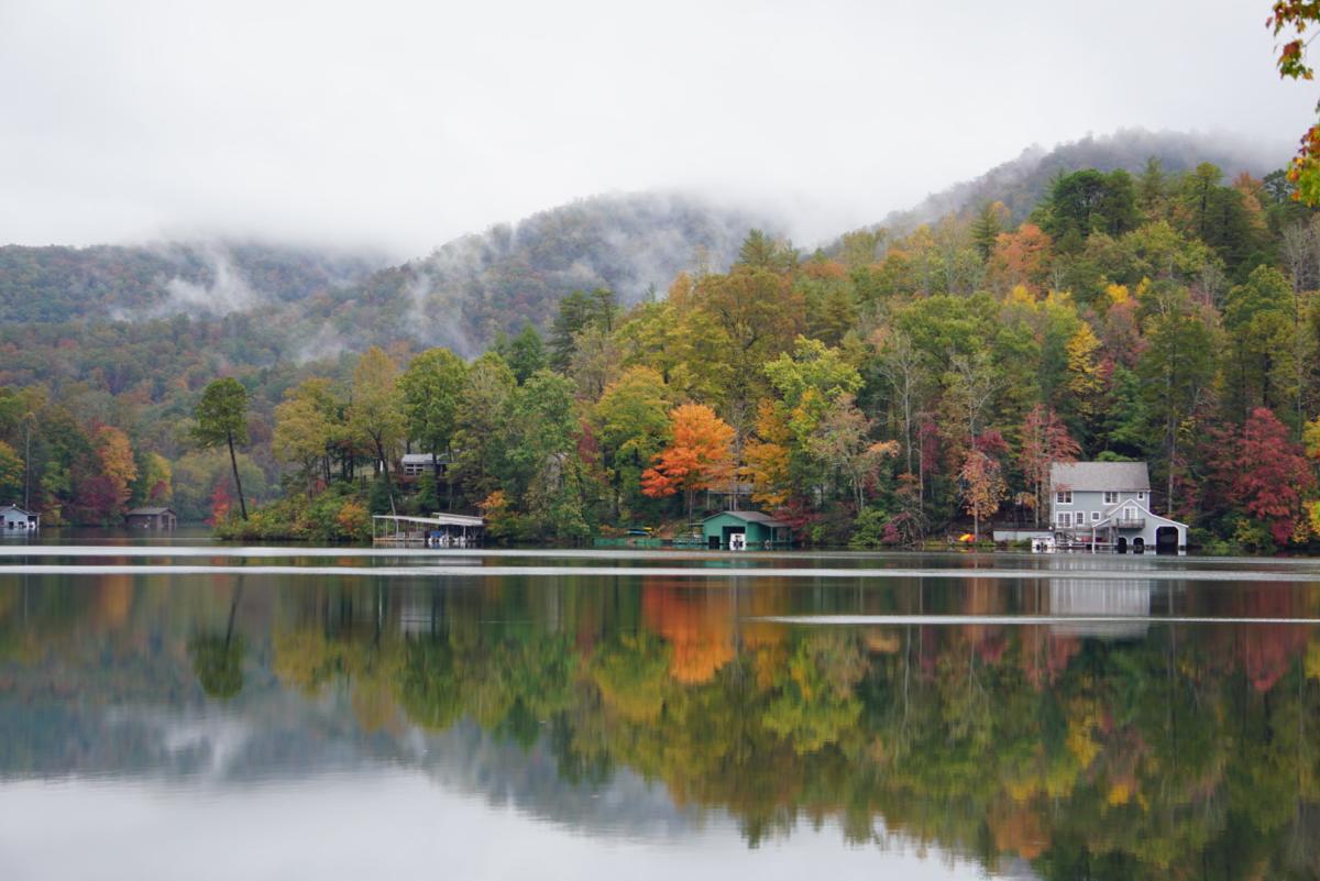 Mist drifts into the autumn foliage along the shore of Lake Lure.