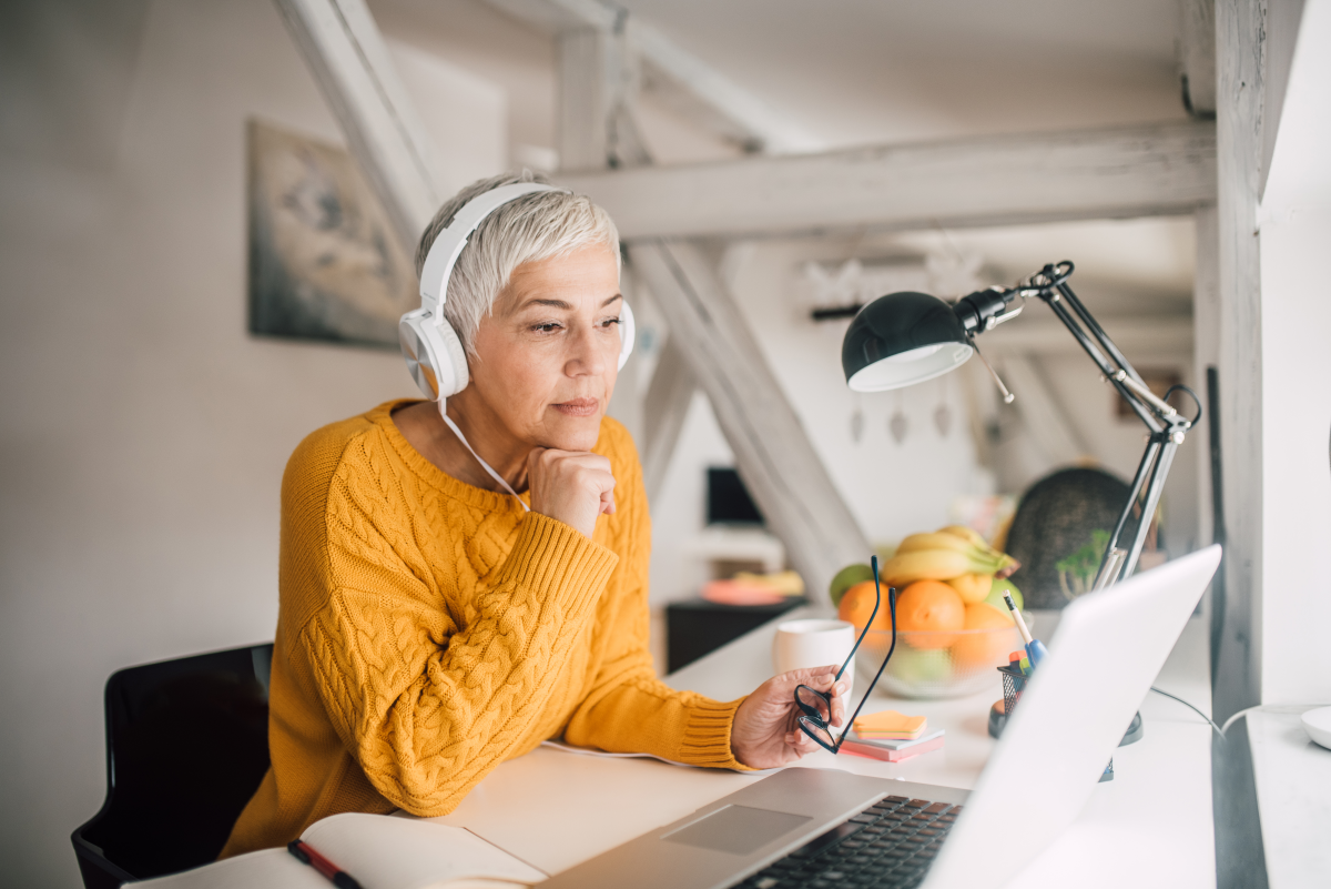 A woman wearing headphones works intently at a laptop.