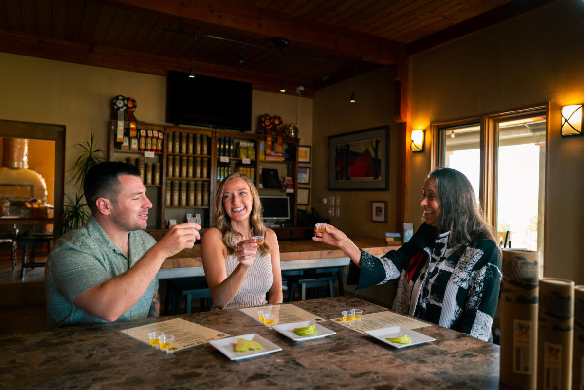 Three people sit at table inside tasting room, sampling olive oil