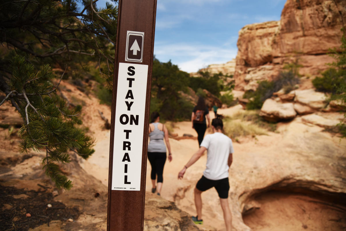 Stay On Trail Sign with hikers in the background