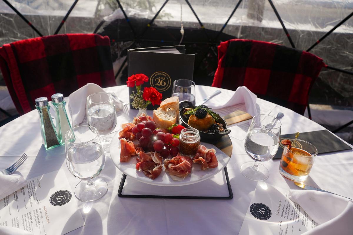 Charcuterie board in the middle of table inside an igloo at The Queensbury Hotel