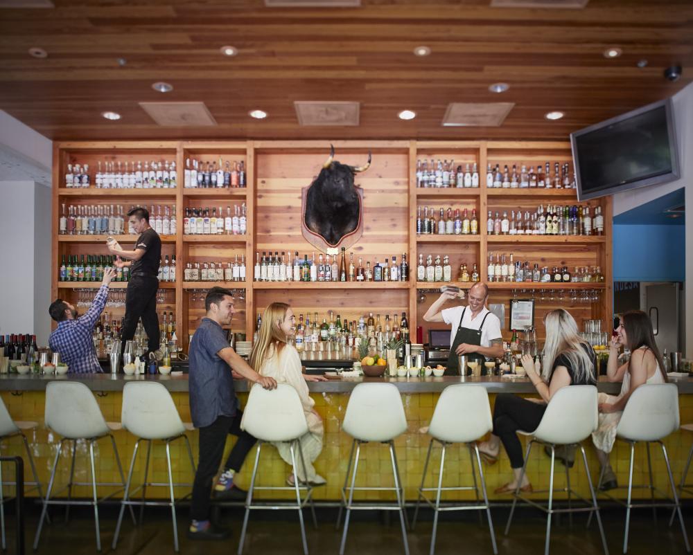 People sitting at bar while bartender shakes cocktail at La Condesa Bar in Austin Texas
