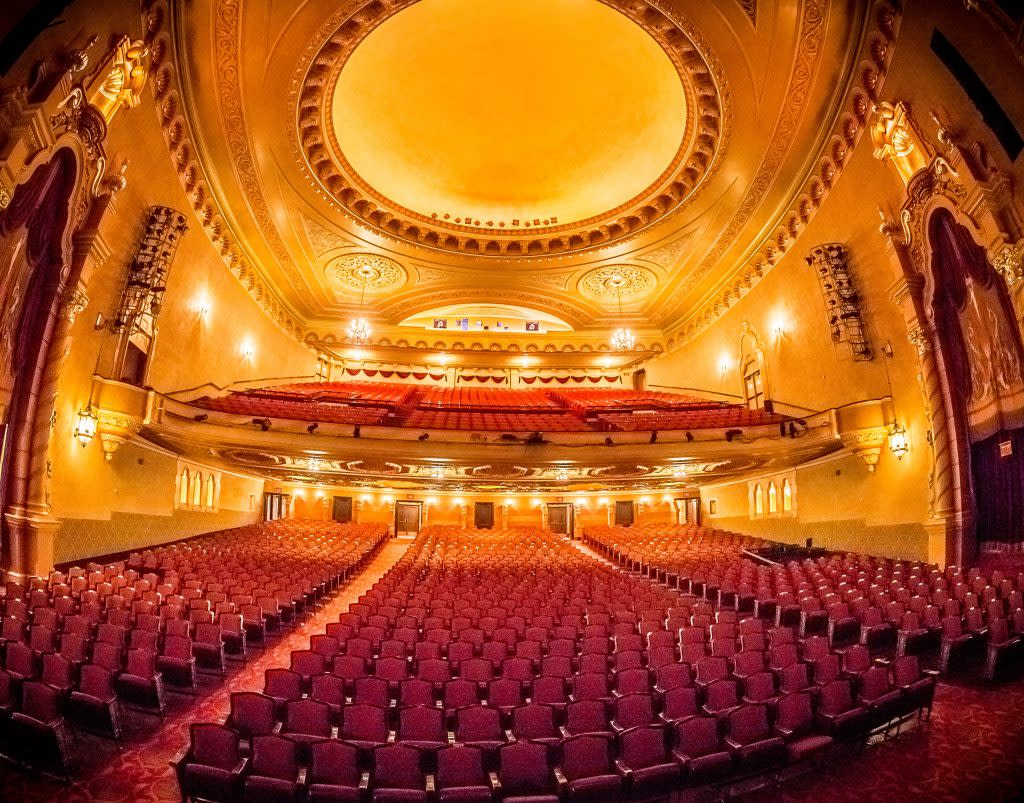 historic theatre view shows ornately decorated walls, domed ceiling and red velvet cushioned theater chairs