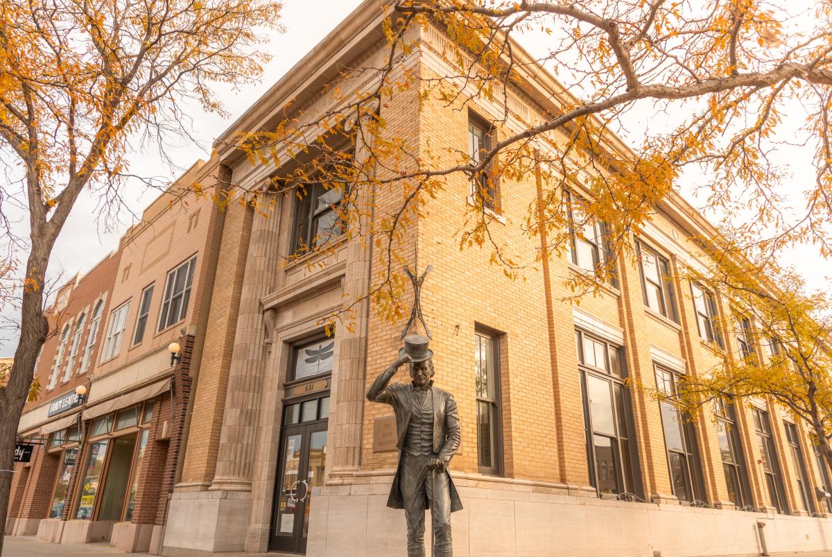 Historic brick building with autumn leaves in foreground. A statue of a President James Moore tipping his hat, creating a warm, nostalgic scene.