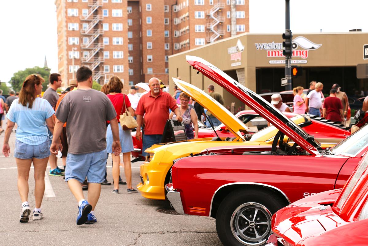 Spectators at the Automobilia Car Show walk by classic cars during the event