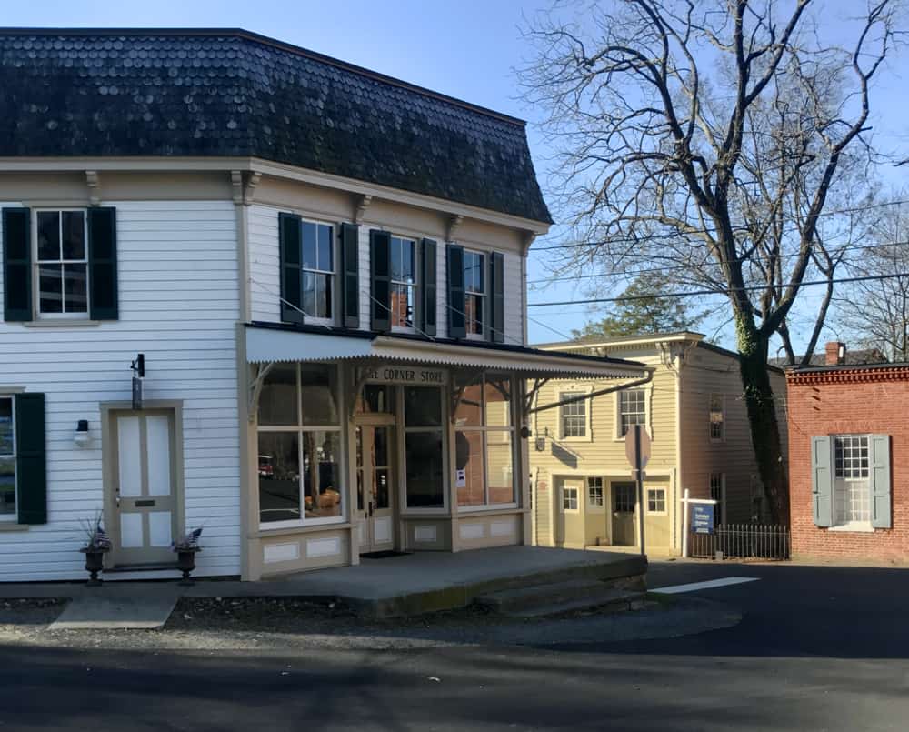 View of the Corner Store in Waterford, VA with its white siding, black tile roof and large front porch