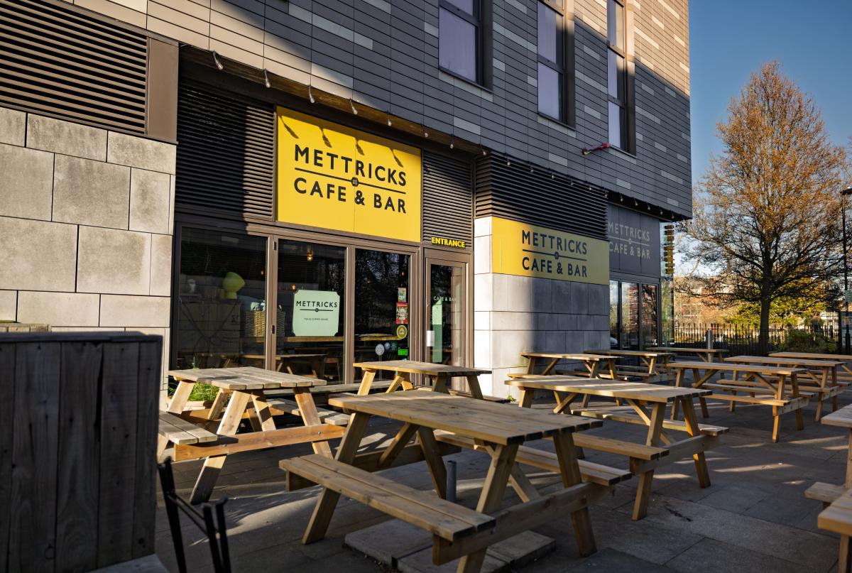 Outdoor seating area filled with picnic benches outside Mettricks Guildhall Cafe