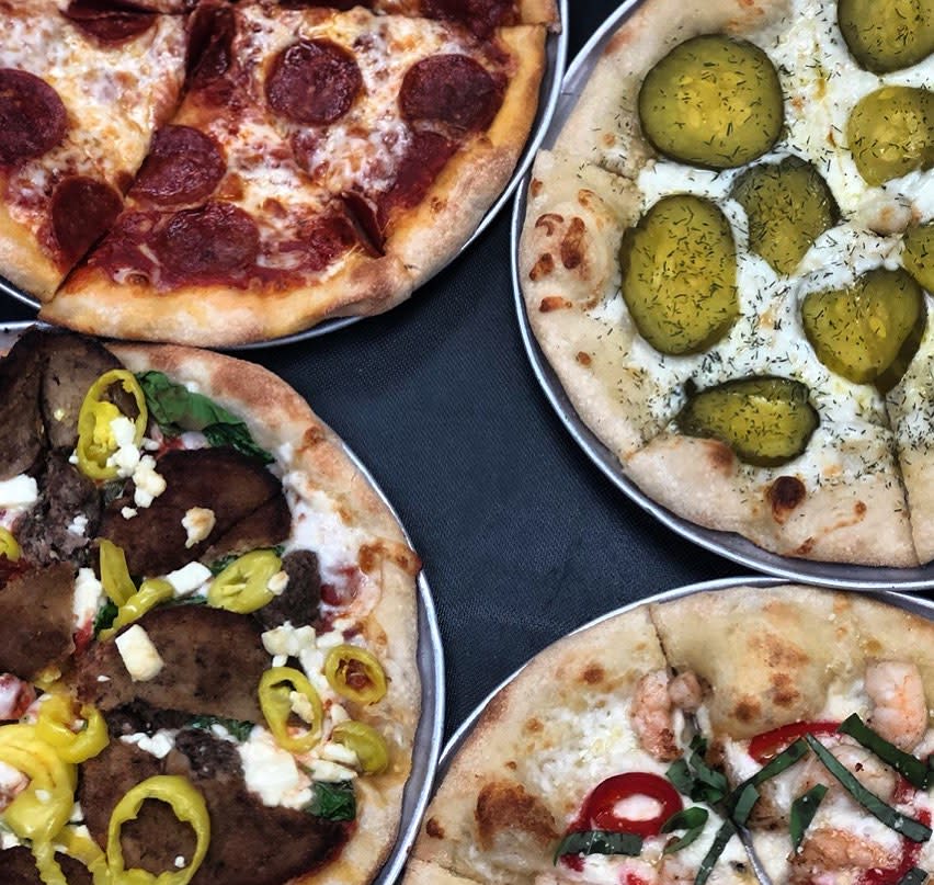 Corners of 4 pizzas topped with pepperoni, pickles, sausage and banana peppers, and shrimp