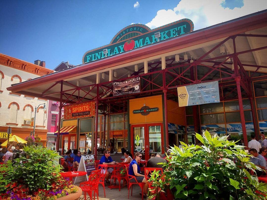 The entrance of Findlay Market during the day with couples sitting at tables surrounded by flowers.