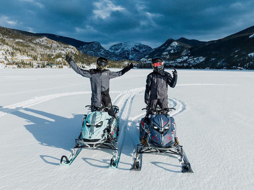 2 men on snowmobiles on frozen Grand Lake with Mount Baldy in the background