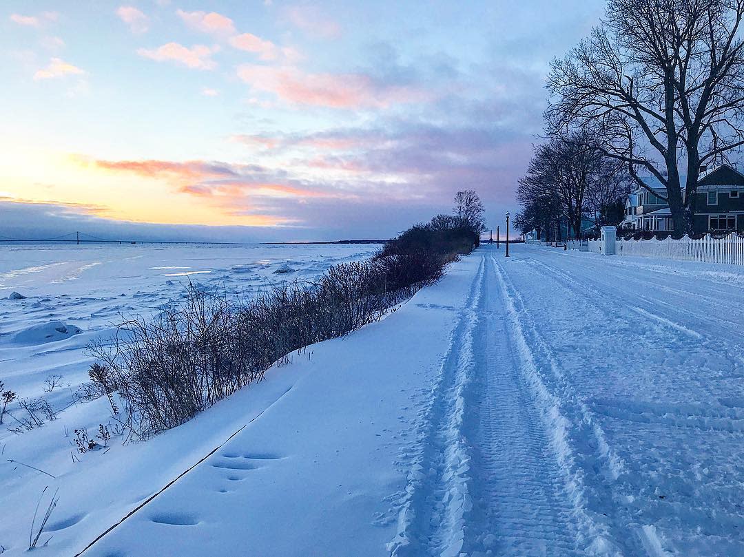 Snowmobile tracks along the Mackinac Island lakeshore with the Mackinac Bridge on the horizon