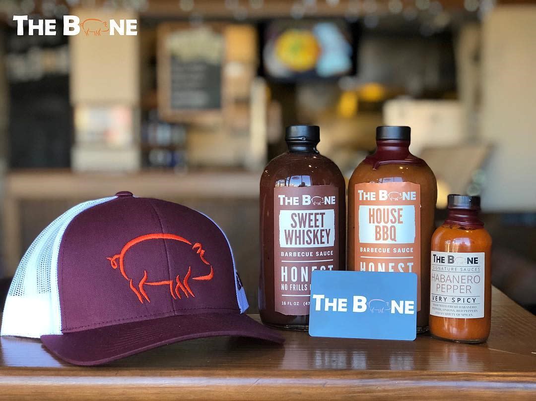 The Bone BBQ hat, BBQ sauce and gift card on a table