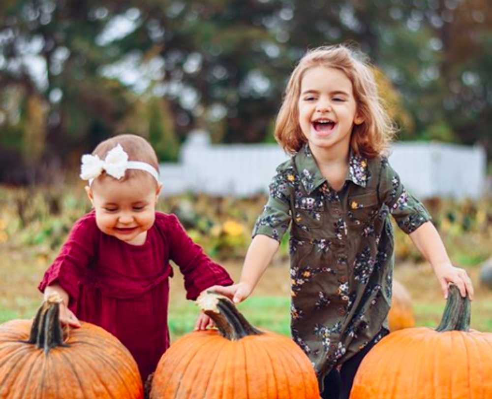 Two young girls with pumpkins at oasis family farm