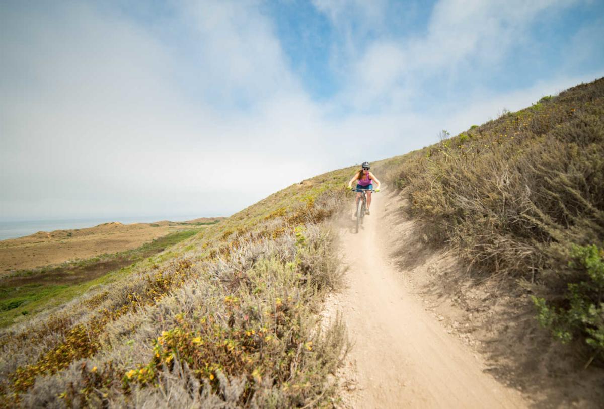 A woman biking down a dirt path in San Luis Obispo