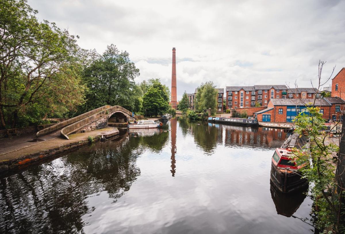 Portland Basin in Tameside, featuring a bridge across water with a canal boat and buildings in the background