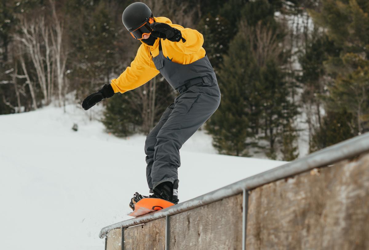 Snowboarder glides across rail at Mont Ripley Terrain Park.