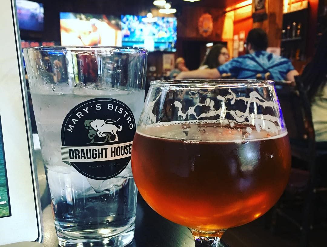 Beer and a glass of water at Mary’s Bistro Draught House on Mackinac Island with TVs in the background