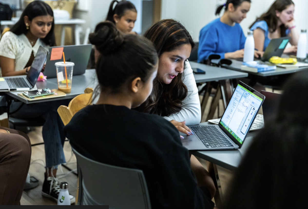 Two students work on a laptop in a modern school classroom