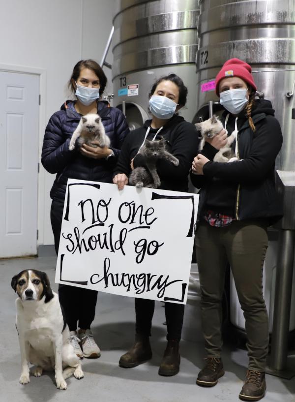 Chehalem staff and pets hold Giving Season sign that reads "no one should go hungry"