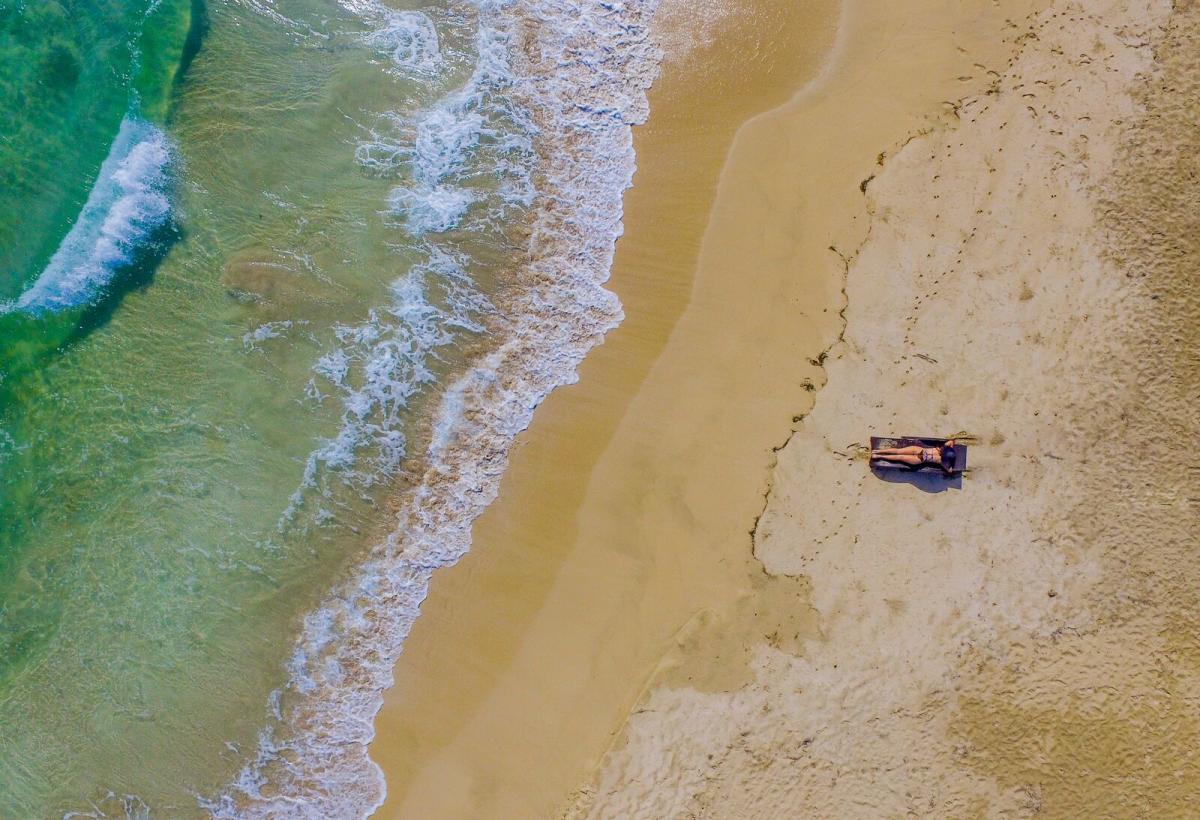 Aerial view of a tourist sunbathing on a pristine beach on Bastimentos Island, Bocas del Toro.