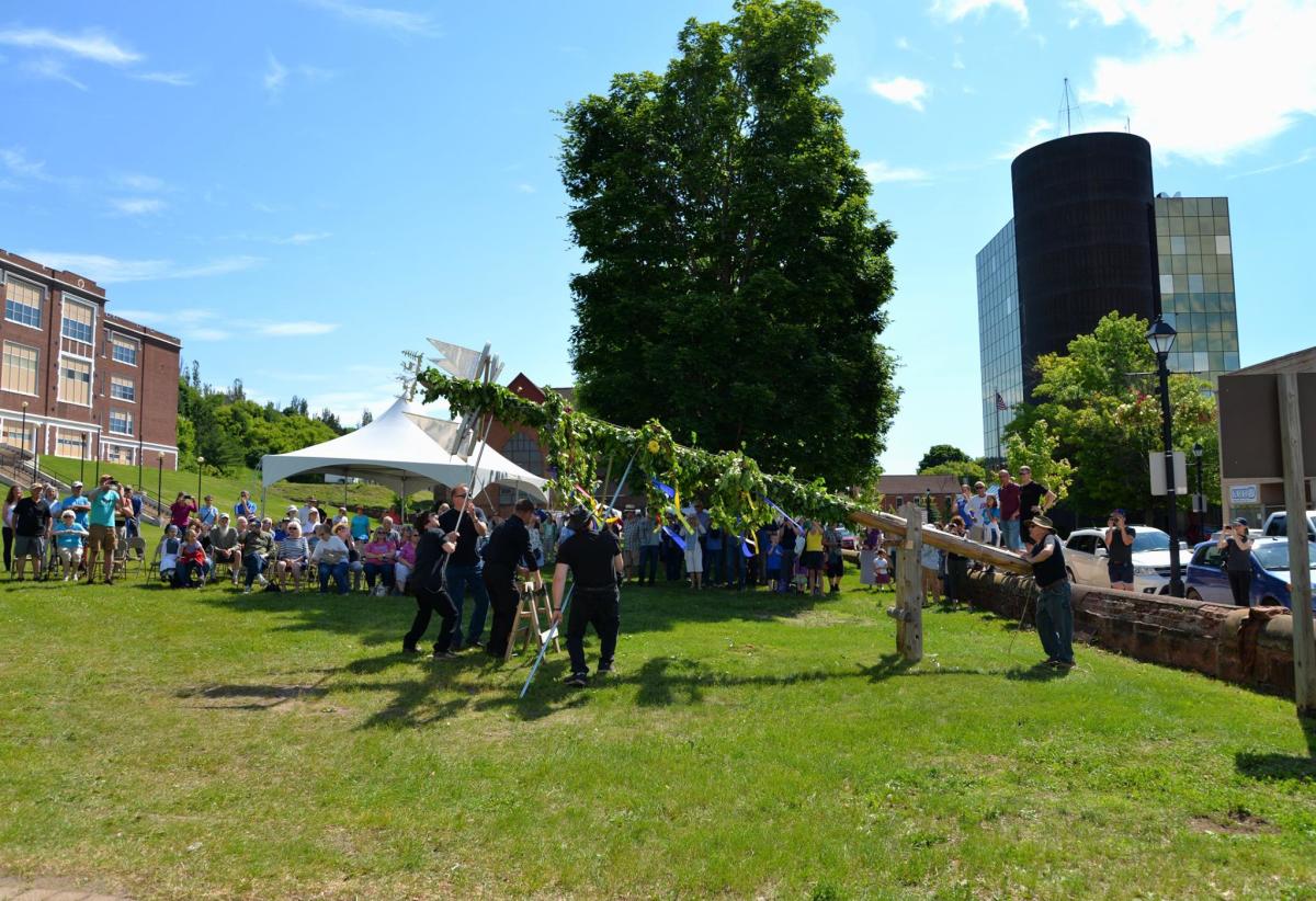 people gather to raise a birch wrapped midsummer pole