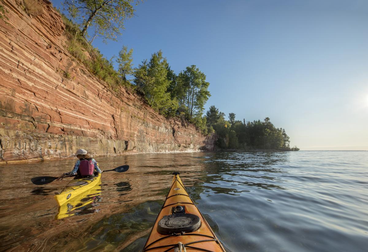 Kayakers paddle along Jacobsville Sandstone Cliffs.