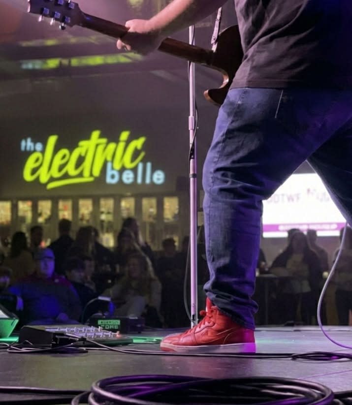 Picture from the stage of a musician playing the guitar in front of a crowd of people
