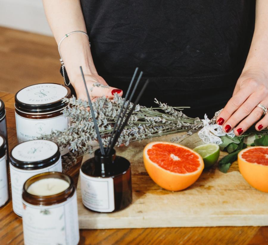 A woman holds flowers on a chopping board, next to cut oranges and candles