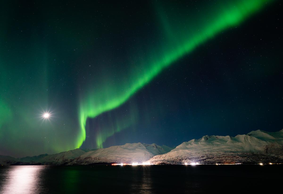 Aurora over a seaside town, port, and mountains