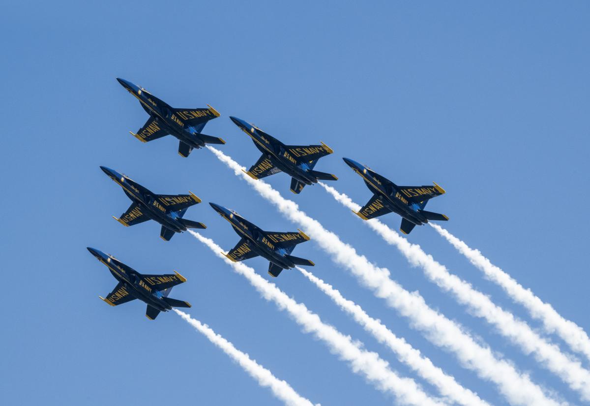Blue Angel airplanes in formation, leaving behind thick white streaks in the sky.