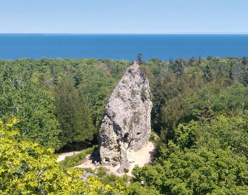 Mackinac Island’s stunning Sugar Loaf rock formation set against green forest and blue water