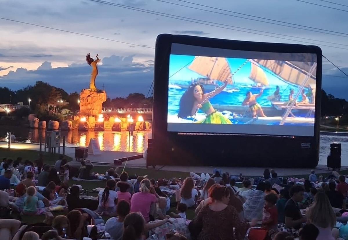 People watch a movie on a screen outside Exploration Place.