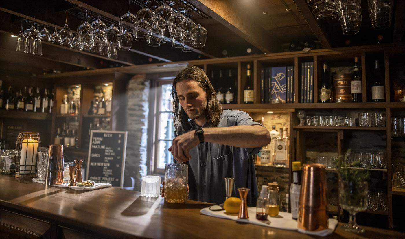 Bartender mixing a cocktail at The Blue Door bar in Arrowtown.