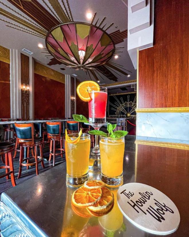 stack of colorful cocktails with orange slices for varnish on a county next to a coaster that reads "The Howlin' Wolf"