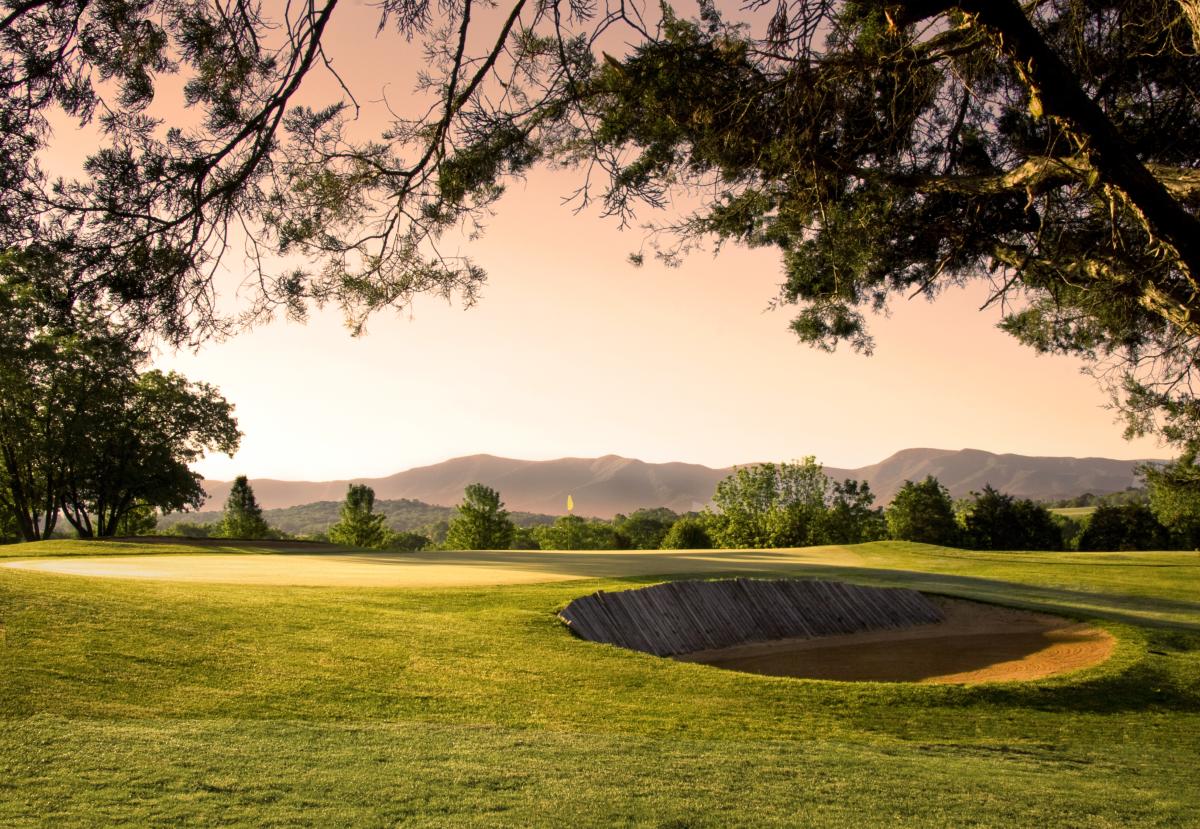 Luray Country Club Resort golf course with sand bunker, yellow flag, rolling mountains, and sunset sky