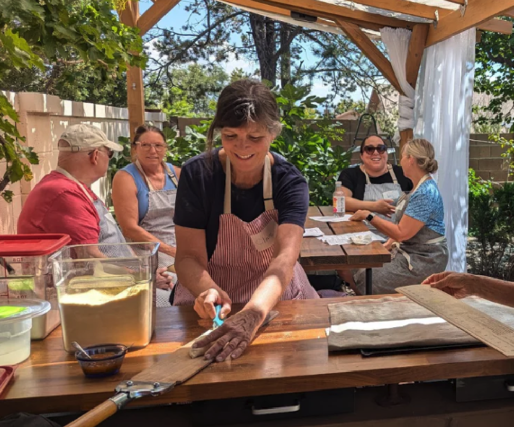 Someone cooks during a cooking class with Sherwood Coffee n Bread while other students chat in the background.