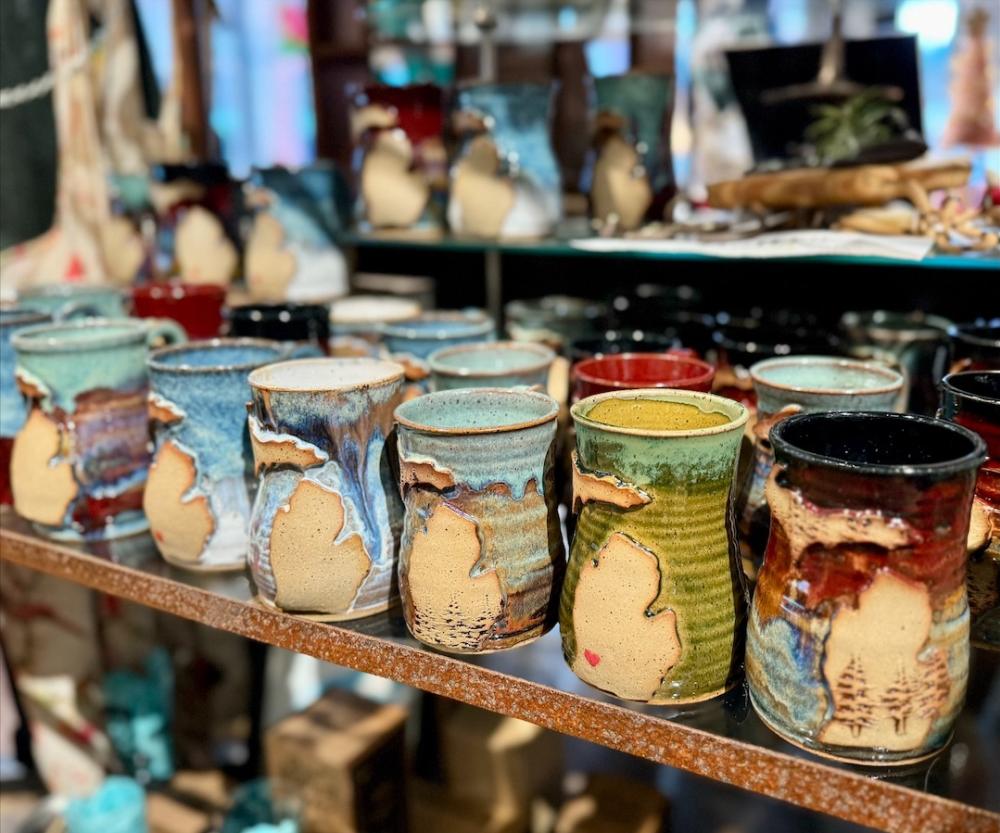 A row of handmade pottery cups sits on a shelf in Earthly Delights by Amy Zane.