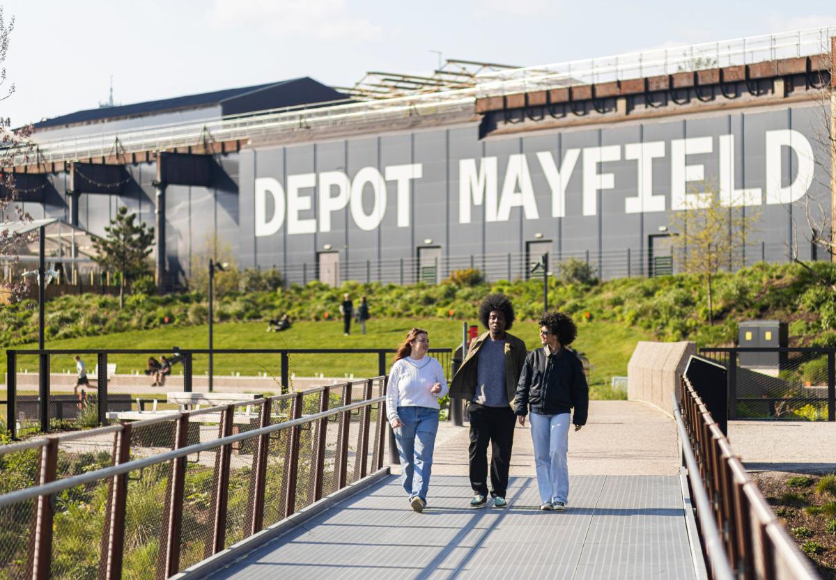 Friends walking along a bridge at Mayfield Park with Depot Mayfield sign in the background