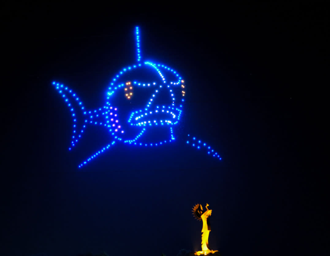 Bright drones light up the sky in the shape of a great white shark above the Keeper of the Plains in Wichita, ks