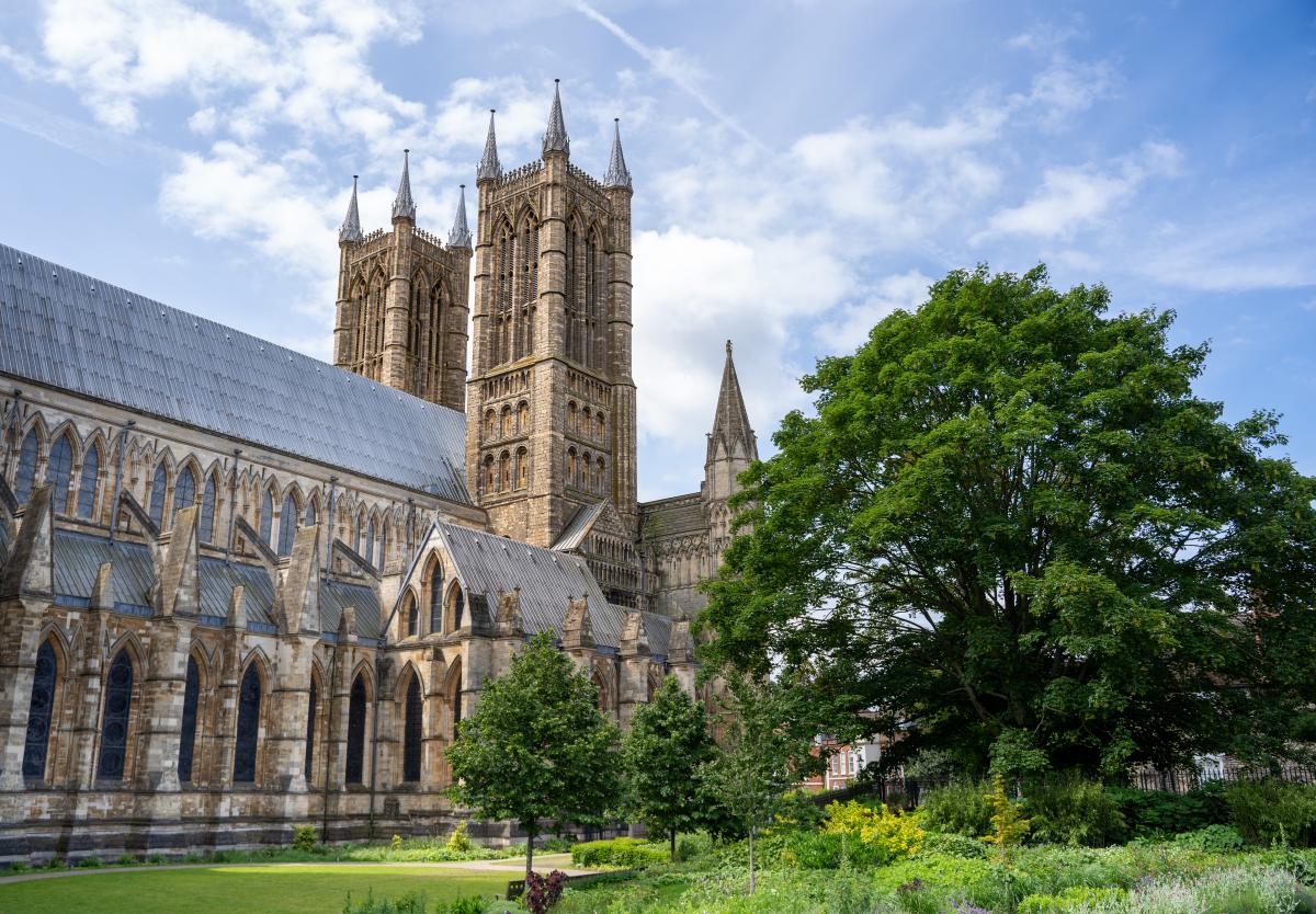 exterior of Lincoln Cathedral towers under blue skies with trees in foreground